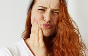 A red-haired young woman with dental pain.